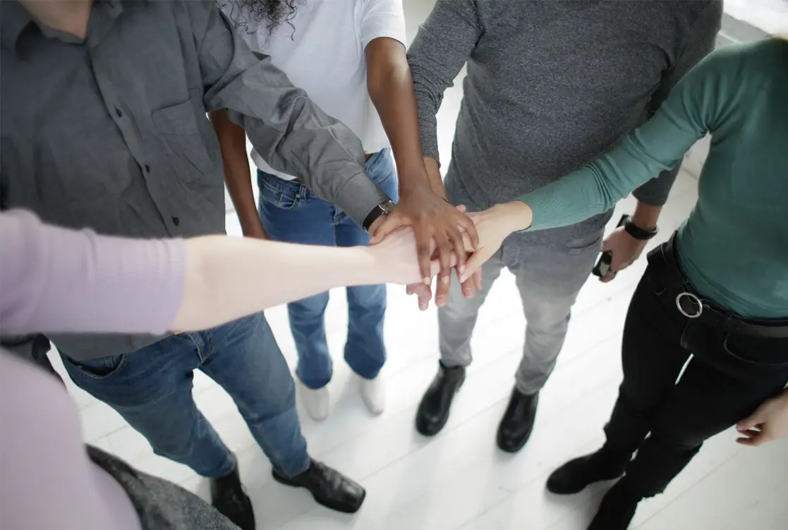 Group of People in a circle with hands in the middle